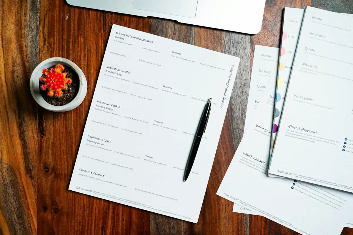 Black pen lying on printed pages spread across a wooden table