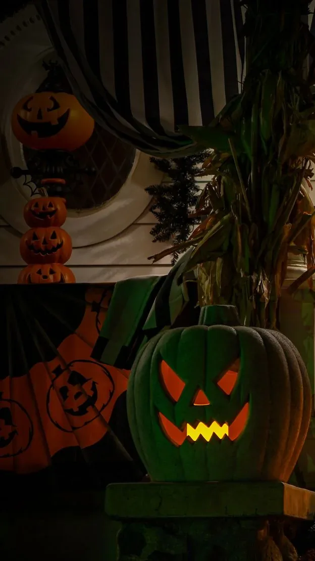 Front porch at night decorated with carved pumpkins