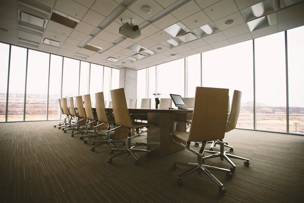 Empty conference room with a long wooden table and black chairs