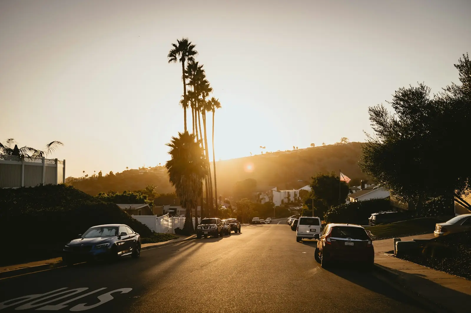 Suburban desert boulevard with light traffic and mountains behind it at sunset