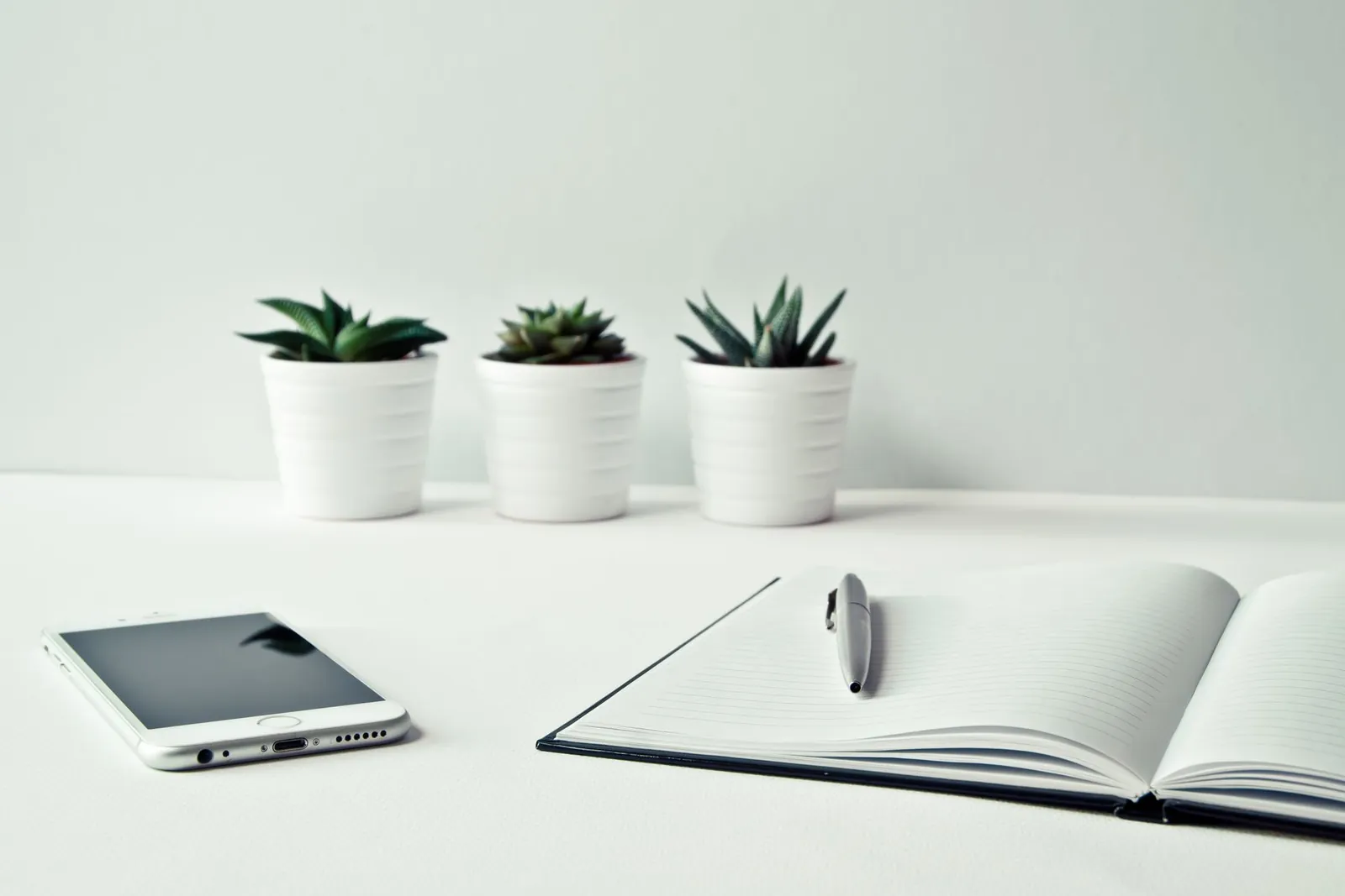 Notebook and pen on a desk beside a phone, no people