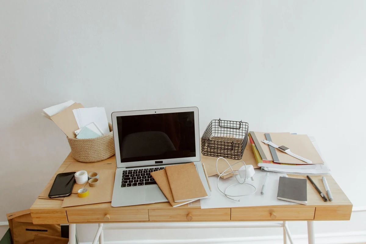 Laptop, notebooks, and office supplies on a bright desk