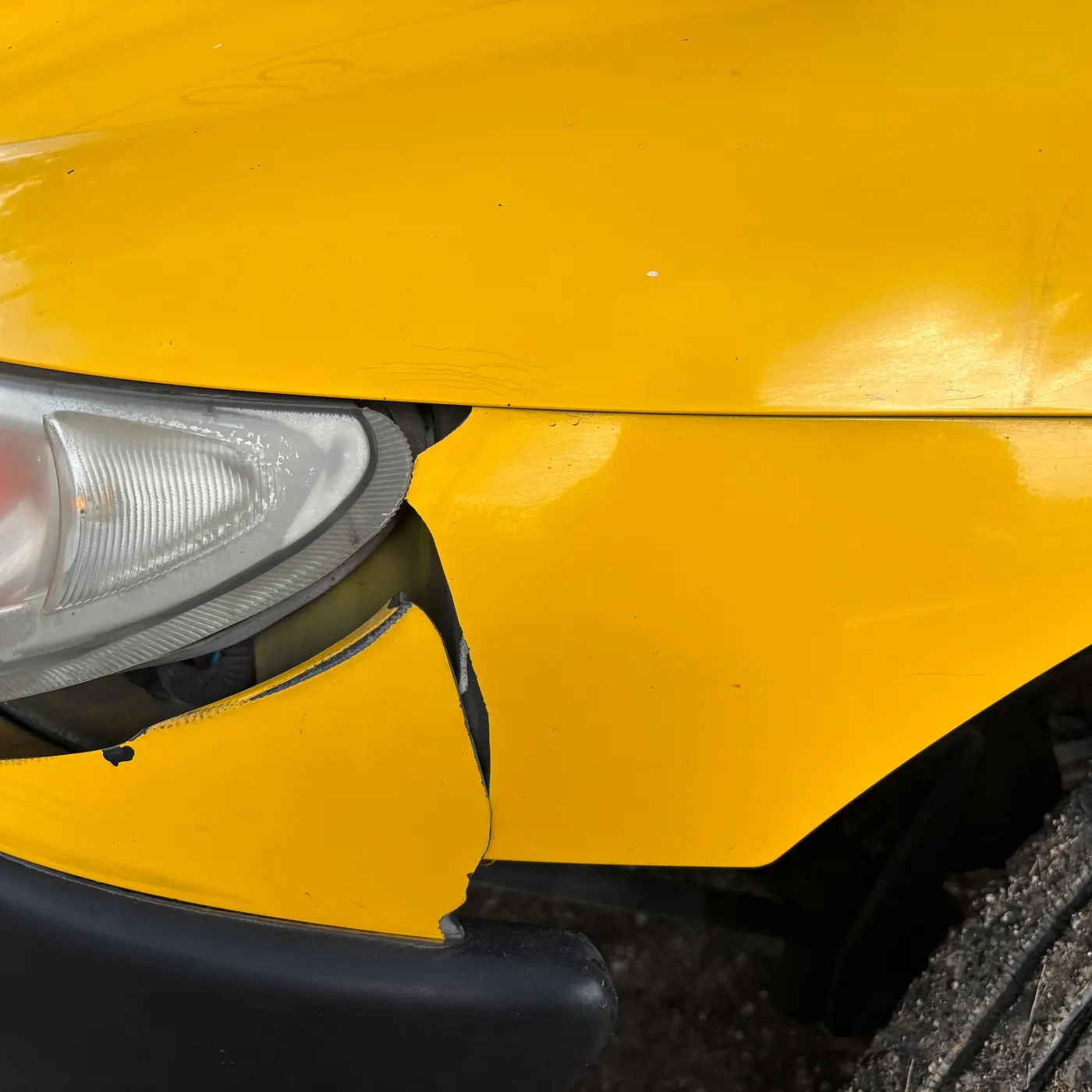 Close-up of the front bumper and headlight of a yellow car
