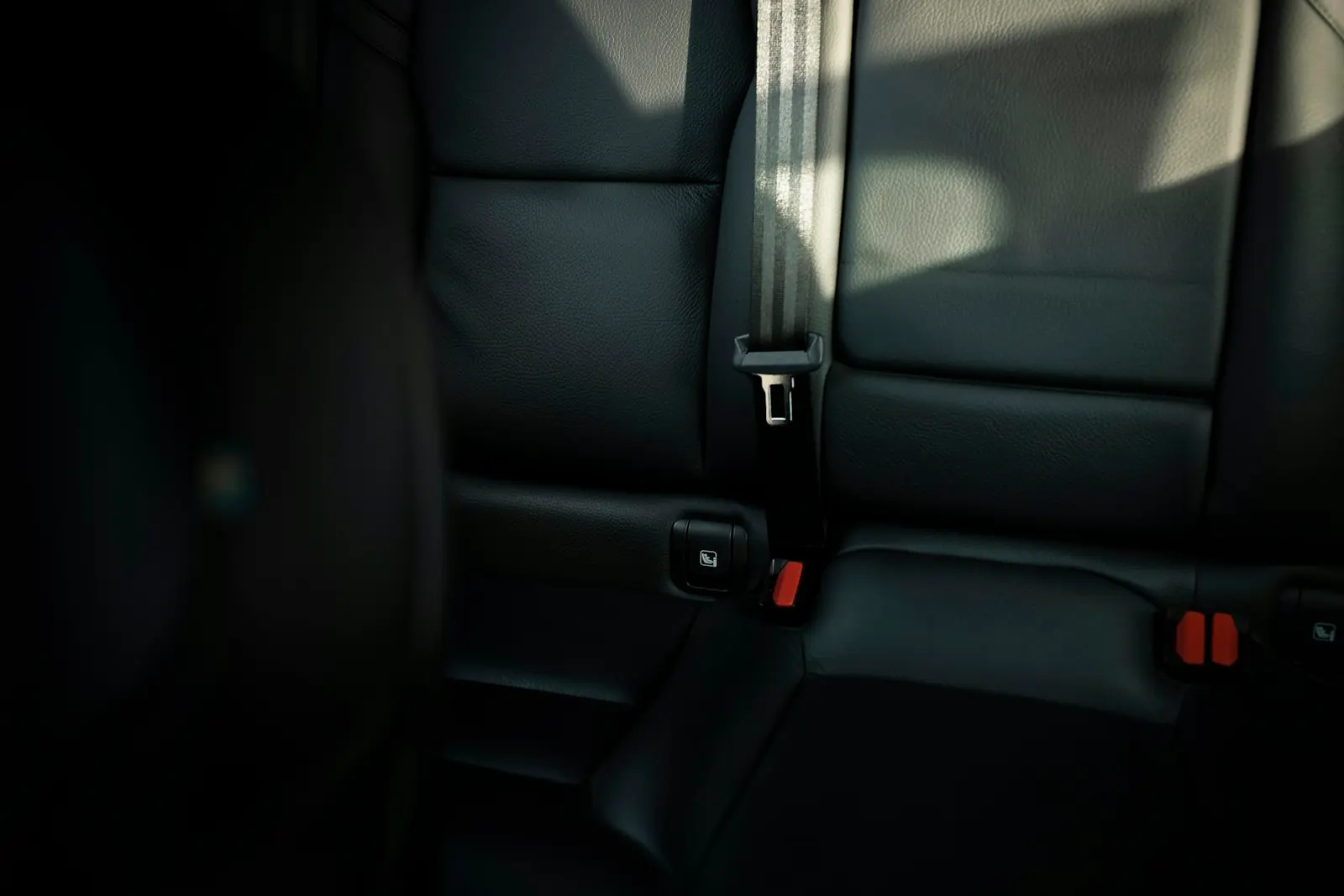 Empty car back seat with a fastened seatbelt in daylight