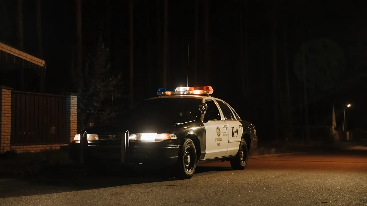 Police car with flashing lights on a dark road at night