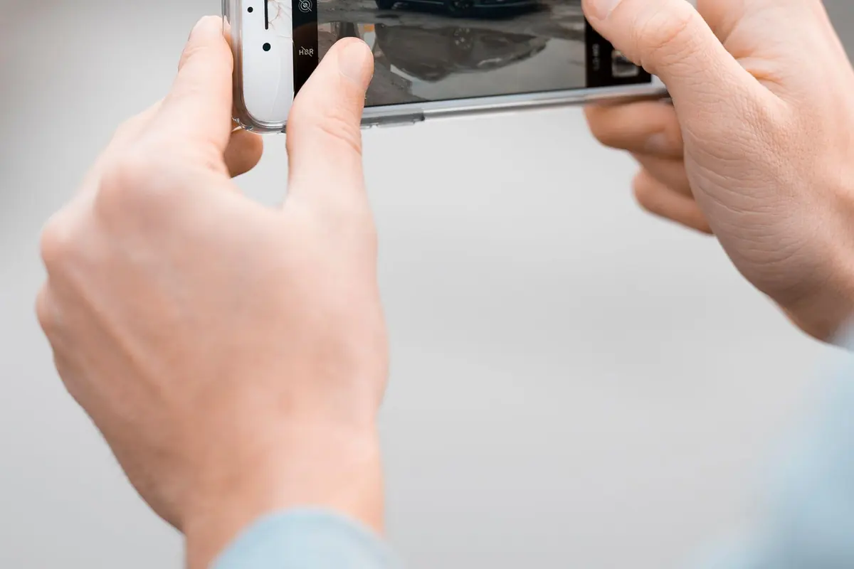 Person photographing minor car damage with a phone after a crash