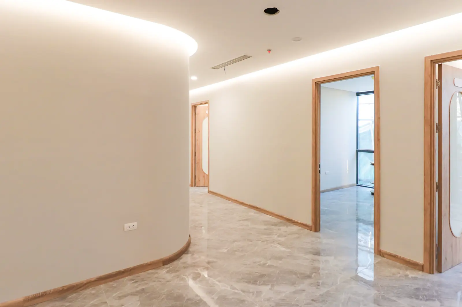 Empty office hallway with a polished marble floor and light wood door frames, no people
