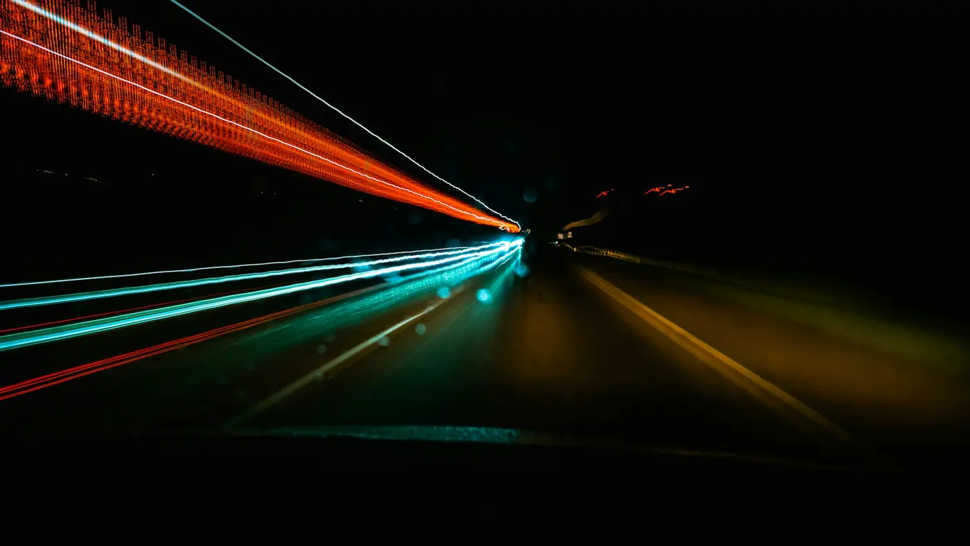 Dark road at night with streaks of vehicle lights