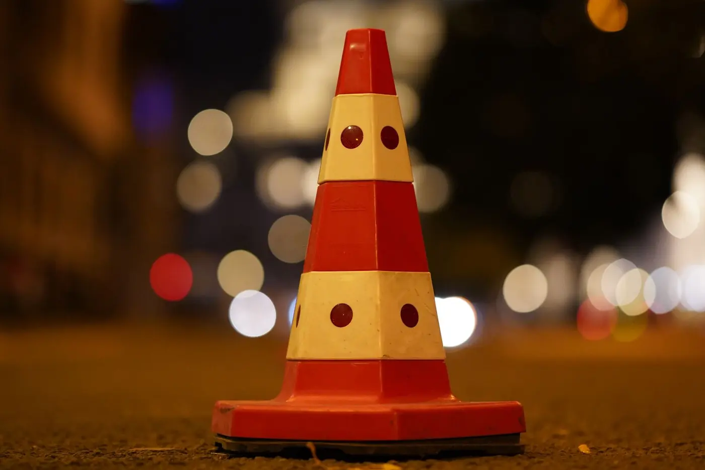 Orange traffic cone on a city street at night